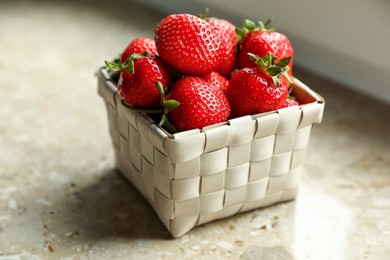 Photo of Fresh juicy strawberries in wicker basket on table, closeup