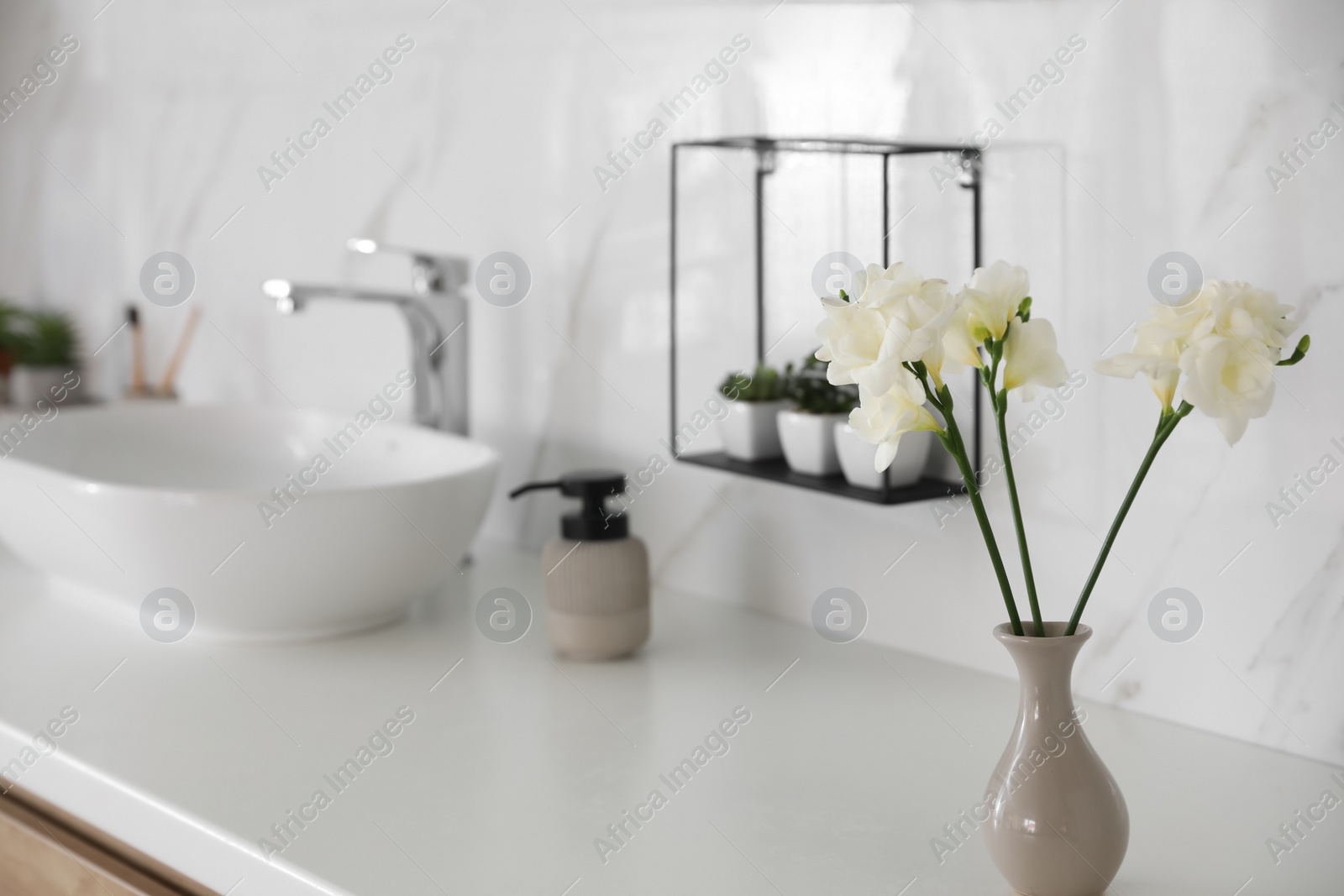 Photo of Beautiful white freesia flowers on countertop in bathroom