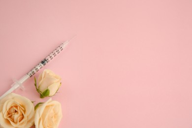 Photo of Medical syringe and rose flowers on pink background, above view. Space for text