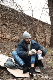 Poor homeless man sitting on cardboard in city park