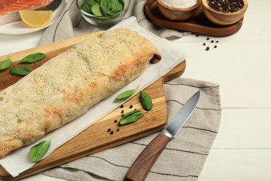 Photo of Delicious strudel with tasty filling and basil served on white wooden table