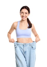 Photo of Happy young woman in big jeans showing her slim body on white background