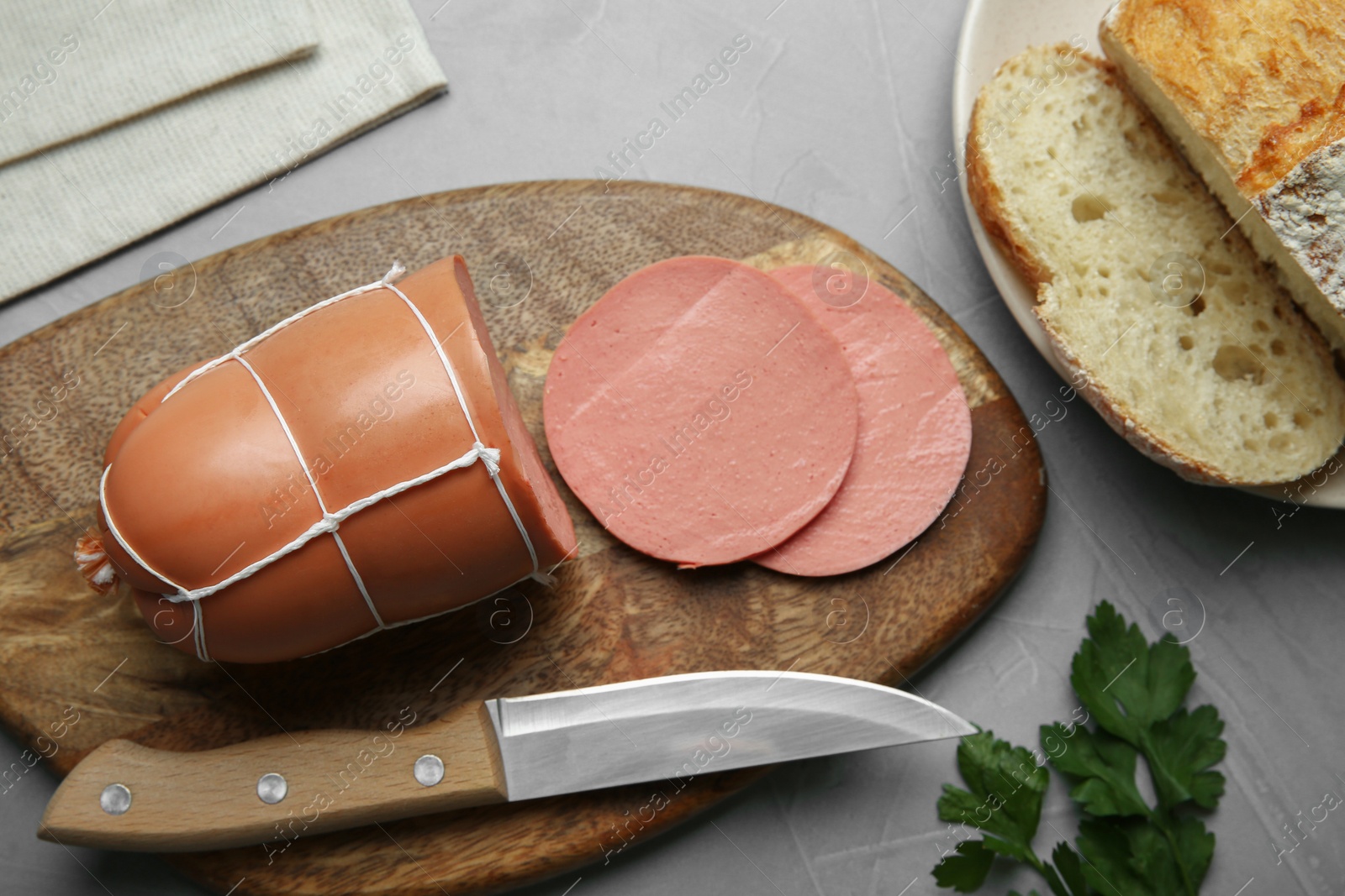 Photo of Board with tasty boiled sausage on light grey textured table, flat lay