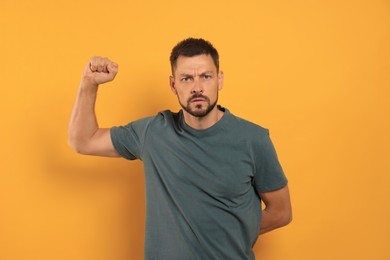 Photo of Man showing his fist on orange background