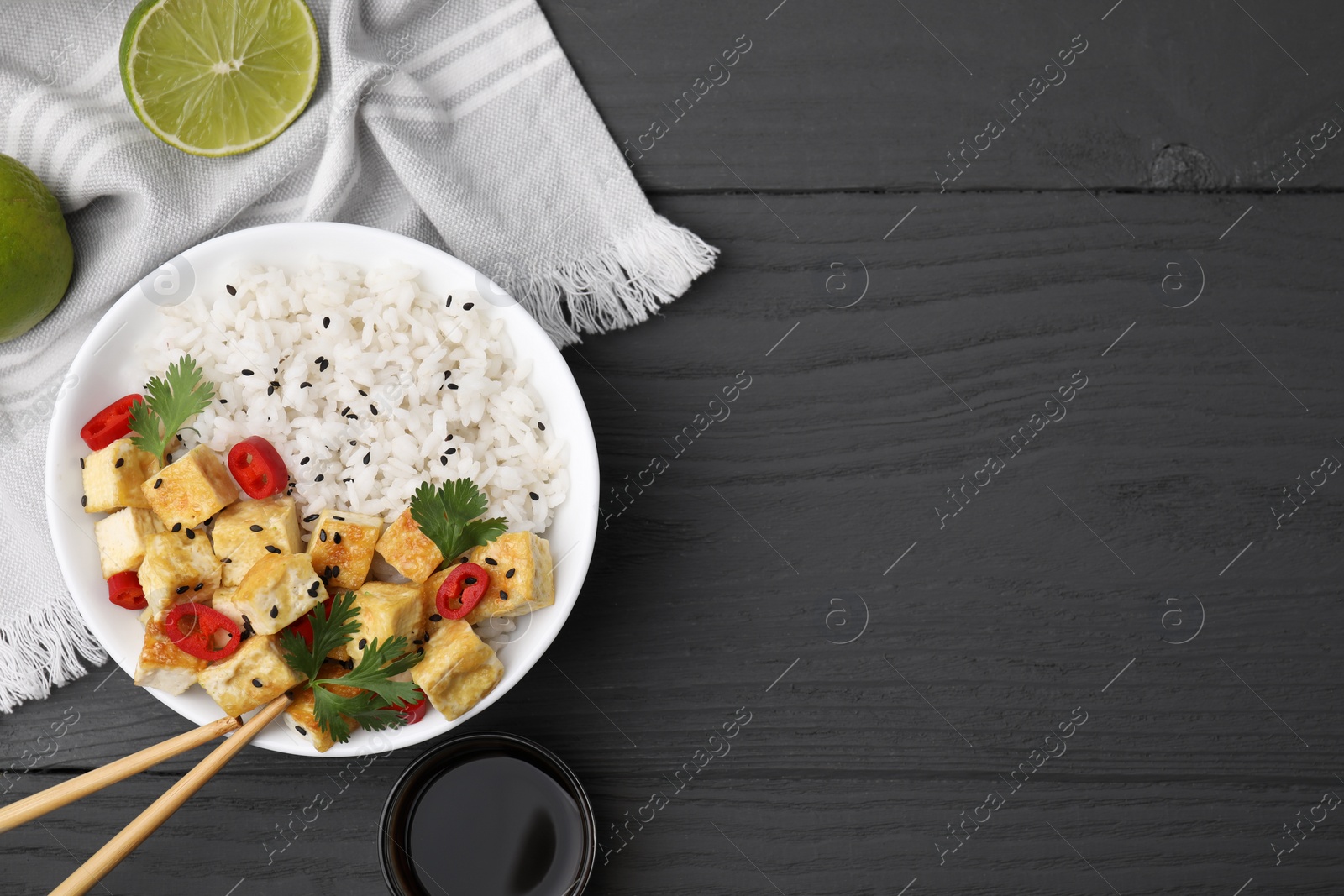 Photo of Delicious rice with fried tofu, chili pepper and parsley served on grey wooden table, flat lay. Space for text