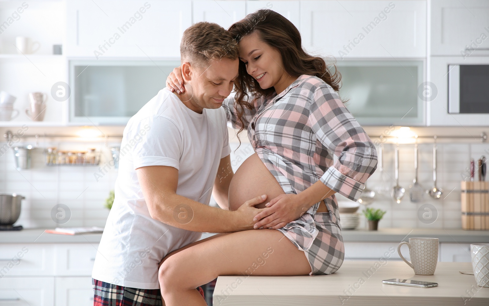 Photo of Pregnant woman with her husband in kitchen. Happy young family