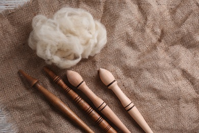 Soft white wool and spindles on table, flat lay. Space for text