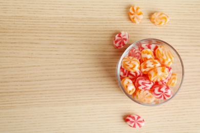 Flat lay composition with glass of delicious colorful candies and space for text on wooden background