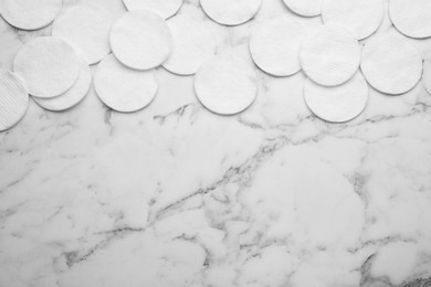 Many clean cotton pads on white marble table, flat lay. Space for text