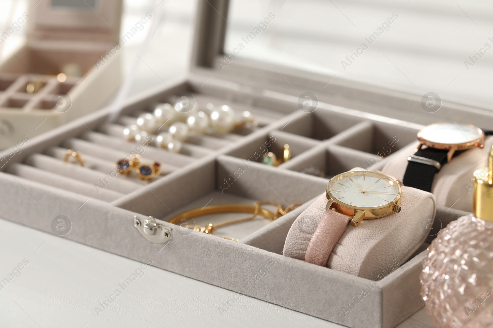 Photo of Jewelry box with many different accessories on white wooden table, closeup