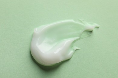 Photo of Sample of face cream on light green background, top view