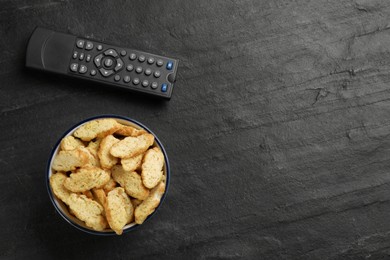 Photo of Modern tv remote control and rusks on black table, flat lay. Space for text