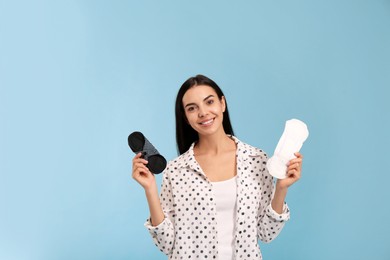 Photo of Young woman with reusable and disposable menstrual pads on light blue background