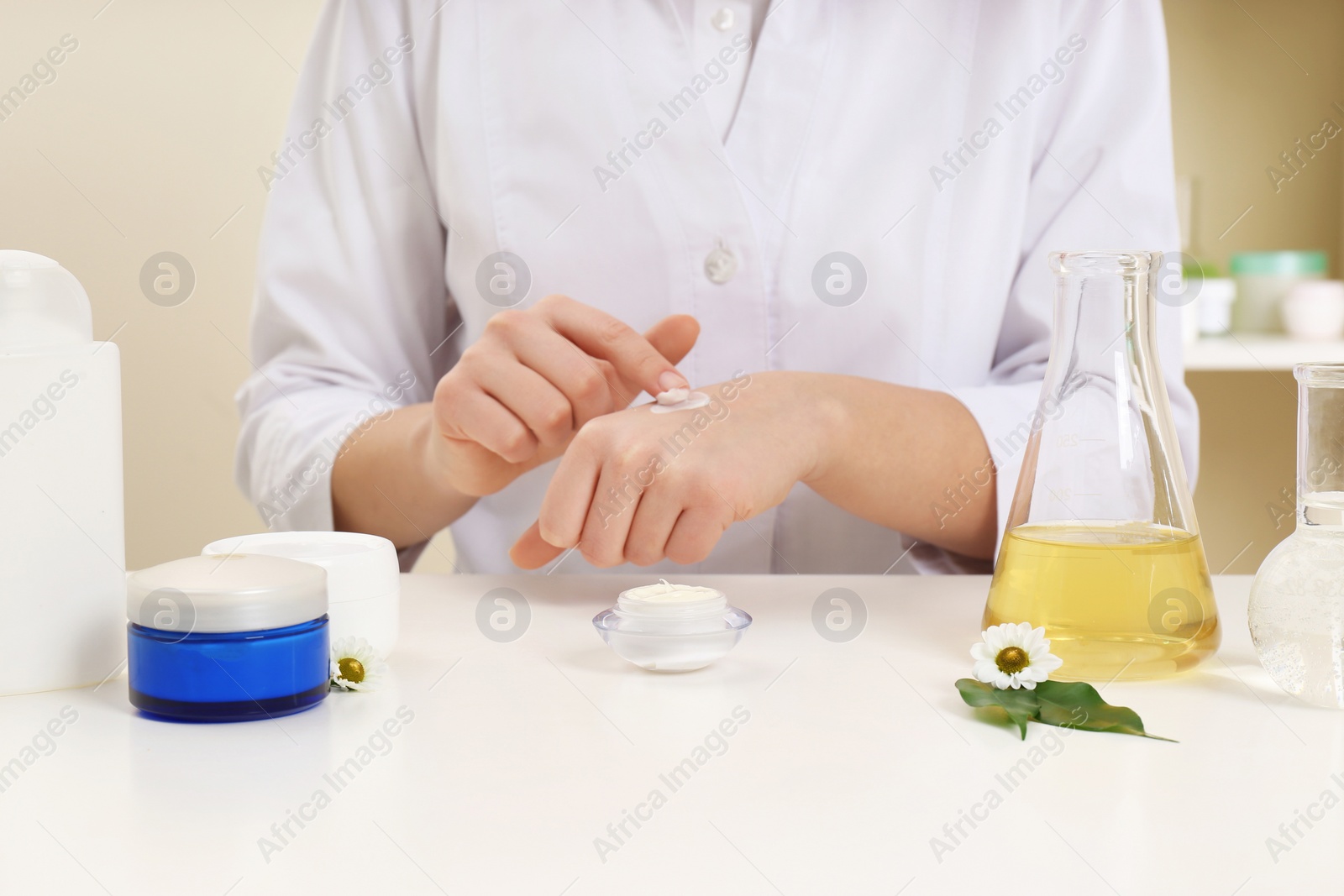 Photo of Female dermatologist testing skin care product at table, closeup