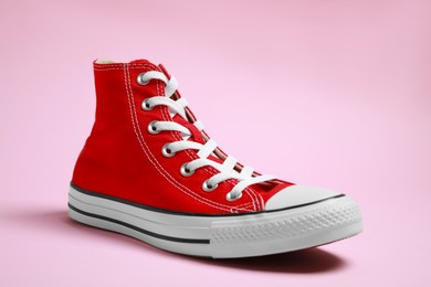 Photo of One new stylish red sneaker on pink background
