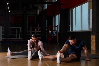 Photo of Couple doing exercise on mats in gym