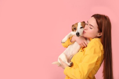 Woman kissing her cute Jack Russell Terrier dog on pink background. Space for text