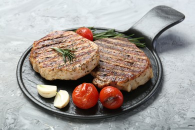 Photo of Delicious grilled pork steaks with spices on gray textured table, closeup