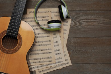 Photo of Composition with guitar and music notations on wooden table, flat lay. Space for text