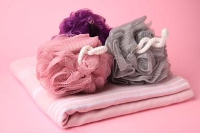 Photo of Colorful shower puffs and towel on pink background
