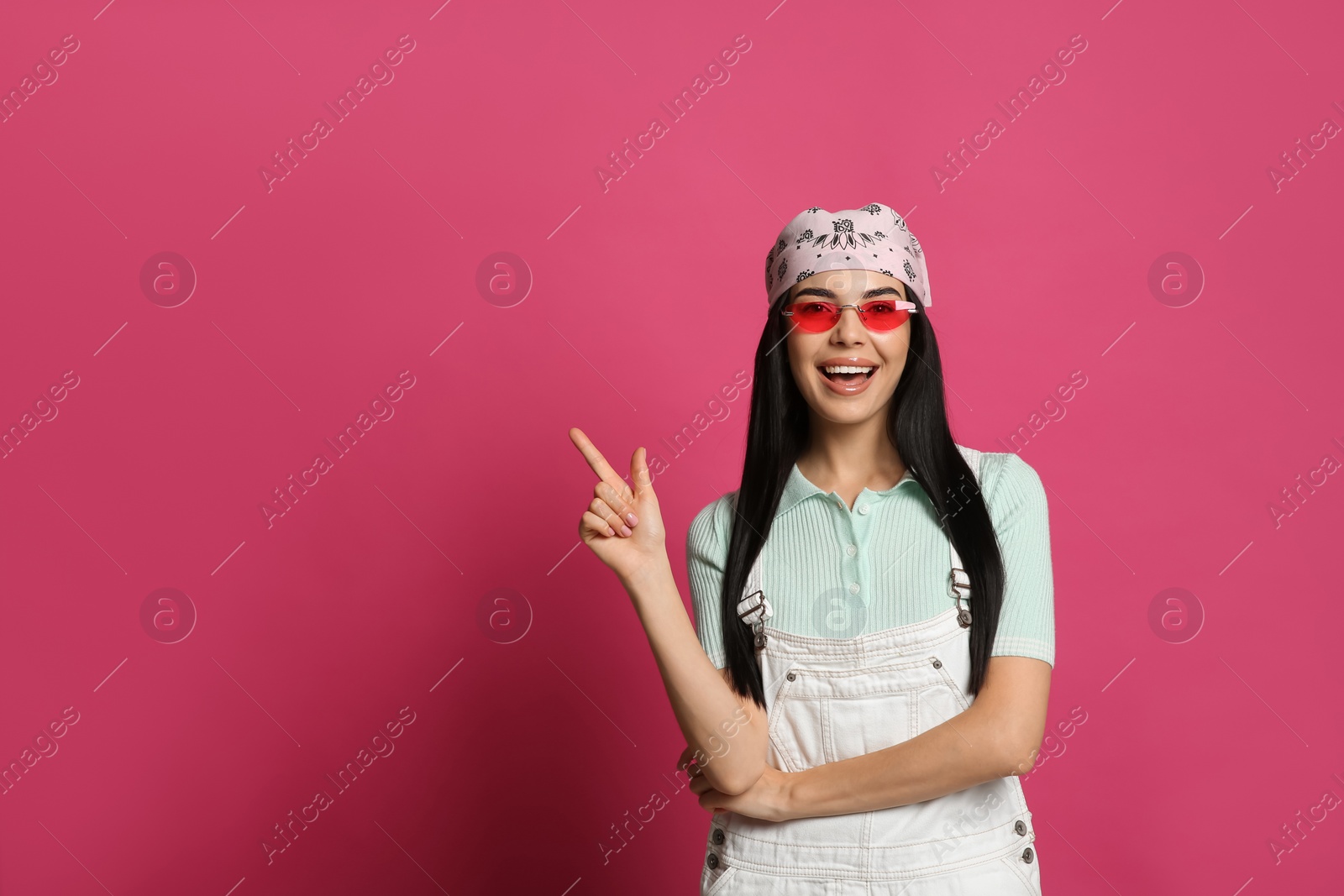 Photo of Young woman wearing stylish bandana and sunglasses on pink background, space for text