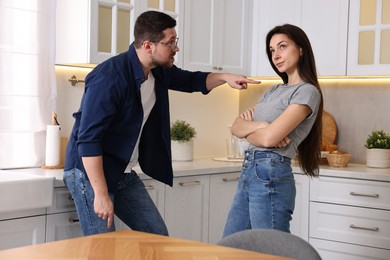 Photo of Annoyed husband screaming at his wife in kitchen. Relationship problems