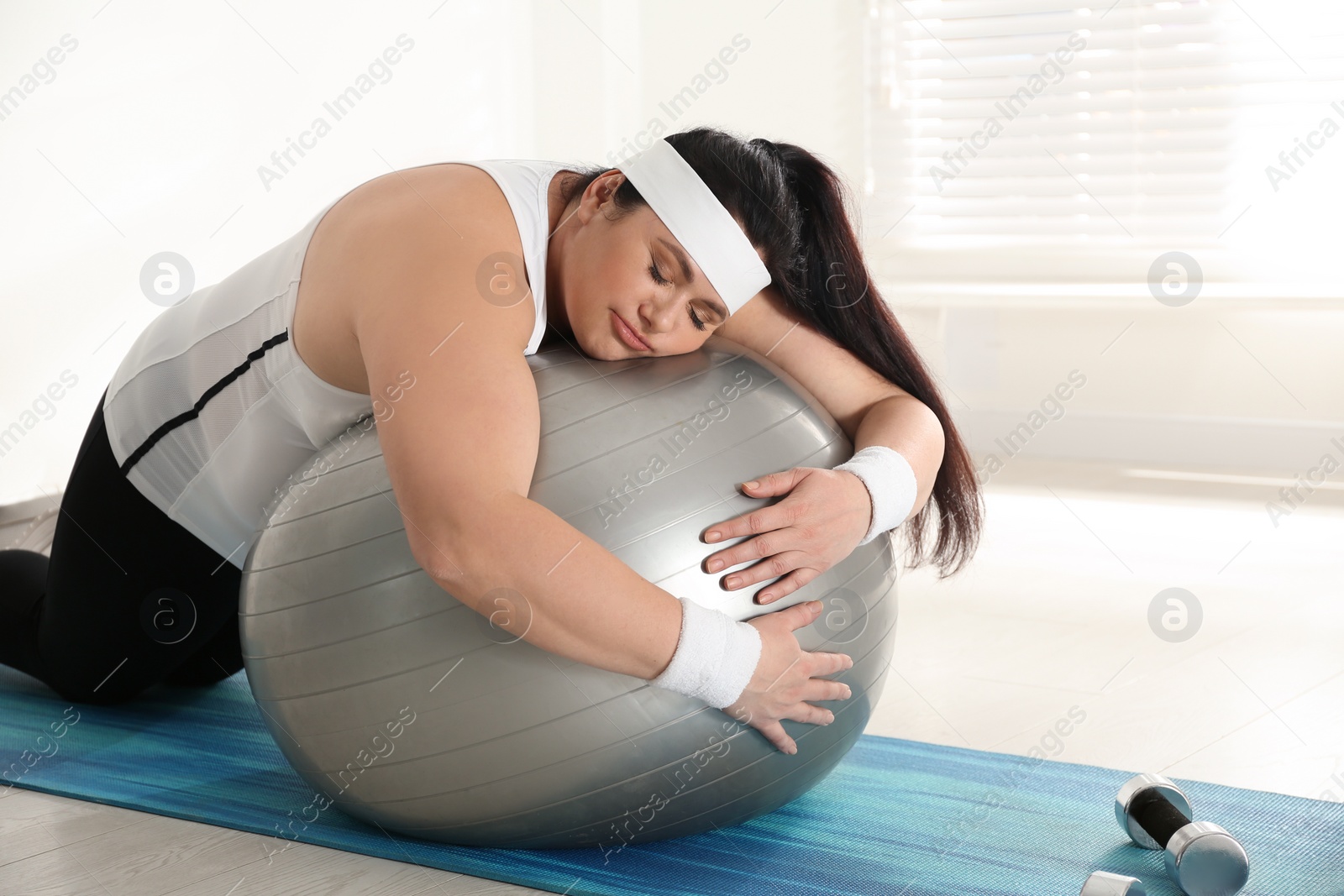 Photo of Lazy overweight woman leaning on fit ball instead of training at gym