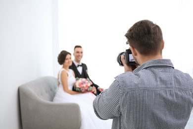 Photo of Professional photographer taking photo of wedding couple in studio