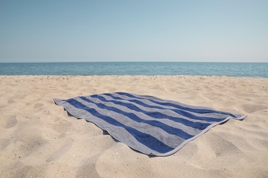 Photo of Striped beach towel on sand near sea