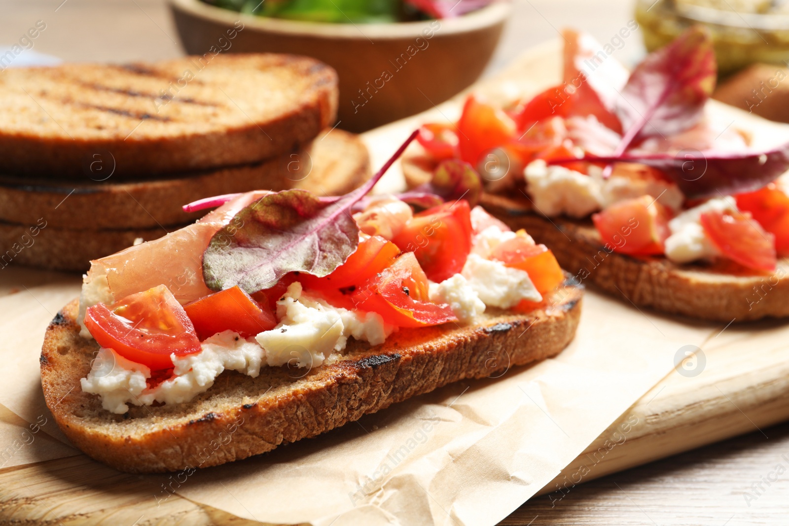 Photo of Serving board with tasty bruschettas on table, closeup