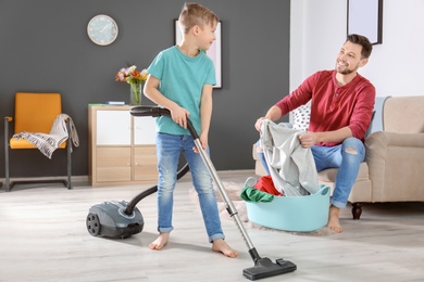 Photo of Little boy and his dad cleaning their house together