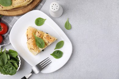 Photo of Piece of delicious puff pastry with spinach on light table, flat lay. Space for text