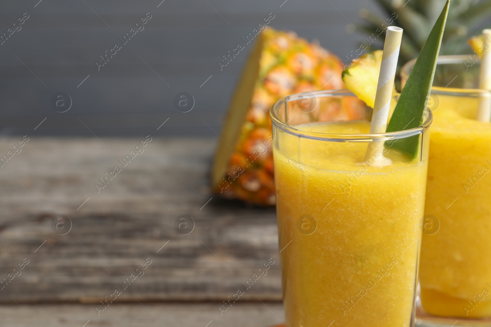 Photo of Tasty pineapple smoothie and cut fruit on table, closeup. Space for text