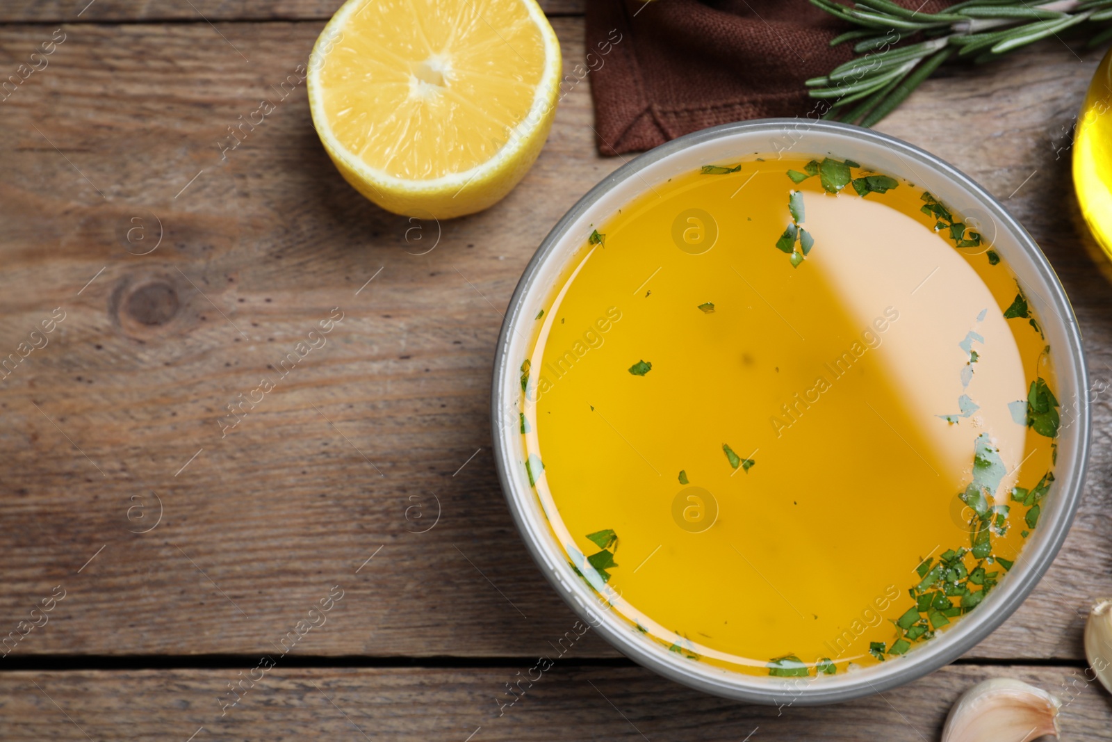 Photo of Bowl of lemon sauce and ingredients on wooden table, flat lay with space for text. Delicious salad dressing