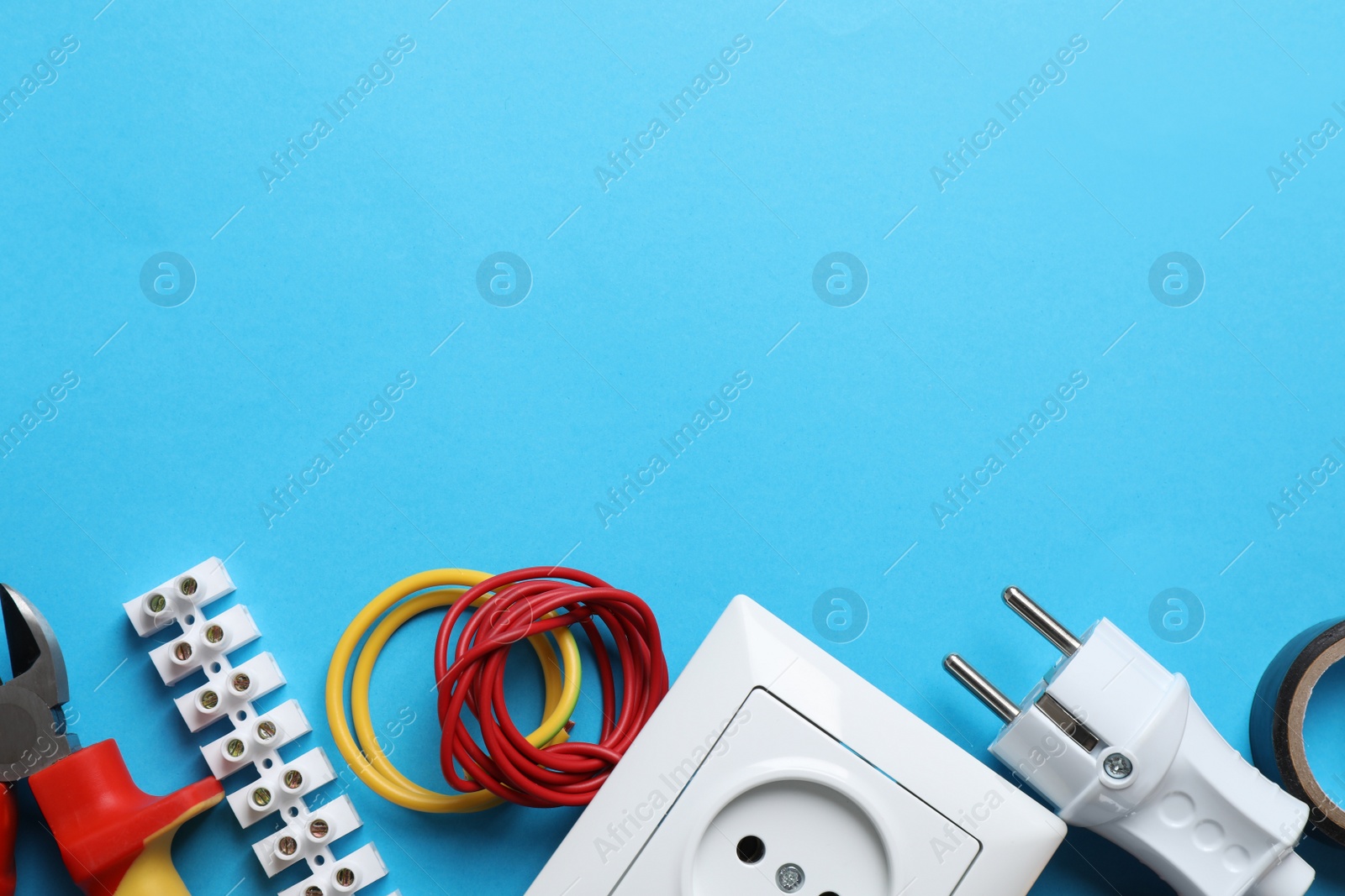 Photo of Set of electrician's tools and accessories on light blue background, flat lay. Space for text