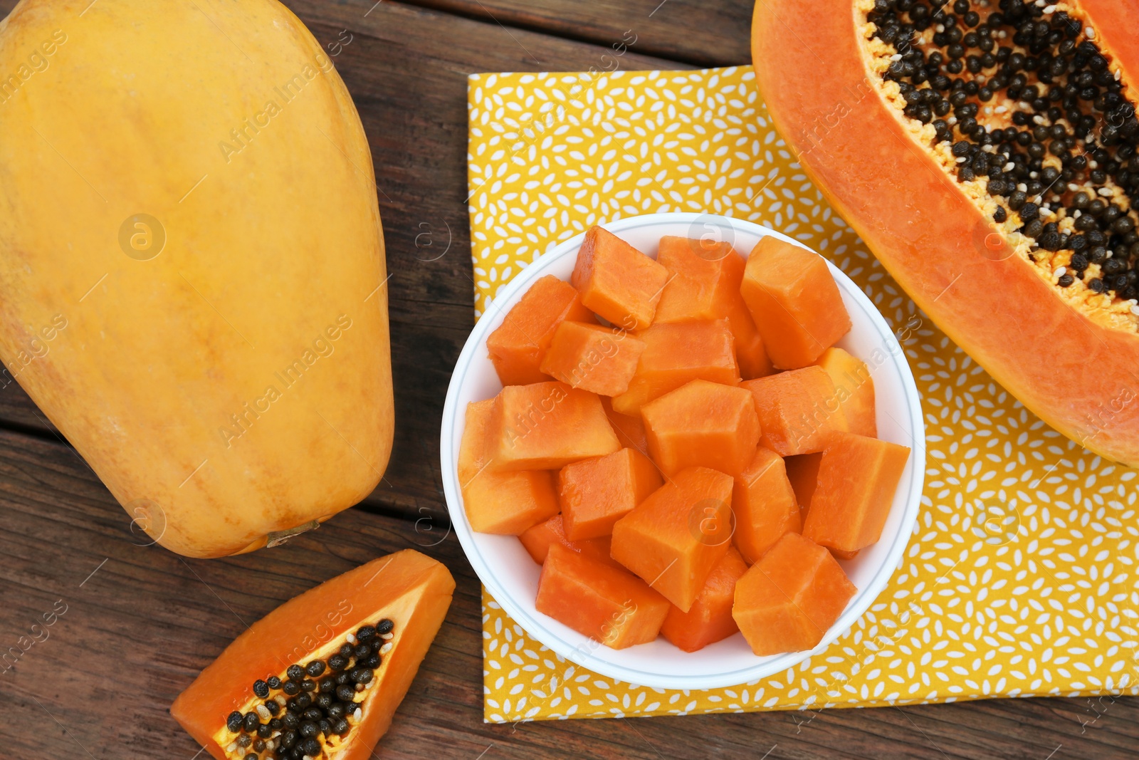 Photo of Tasty whole and cut papaya fruits on wooden table, flat lay