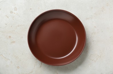 Photo of Empty brown ceramic plate on light grey table, top view