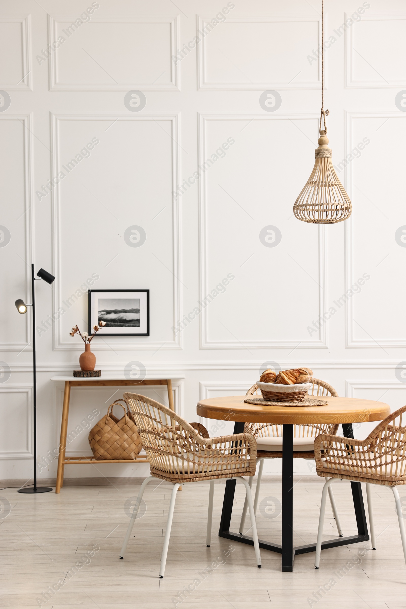 Photo of Dining room interior with wooden table and wicker chairs