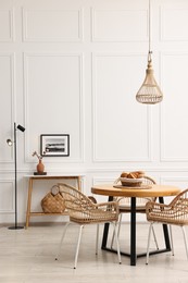 Photo of Dining room interior with wooden table and wicker chairs