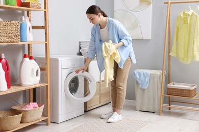 Beautiful woman with sweatshirt near washing machine in laundry room