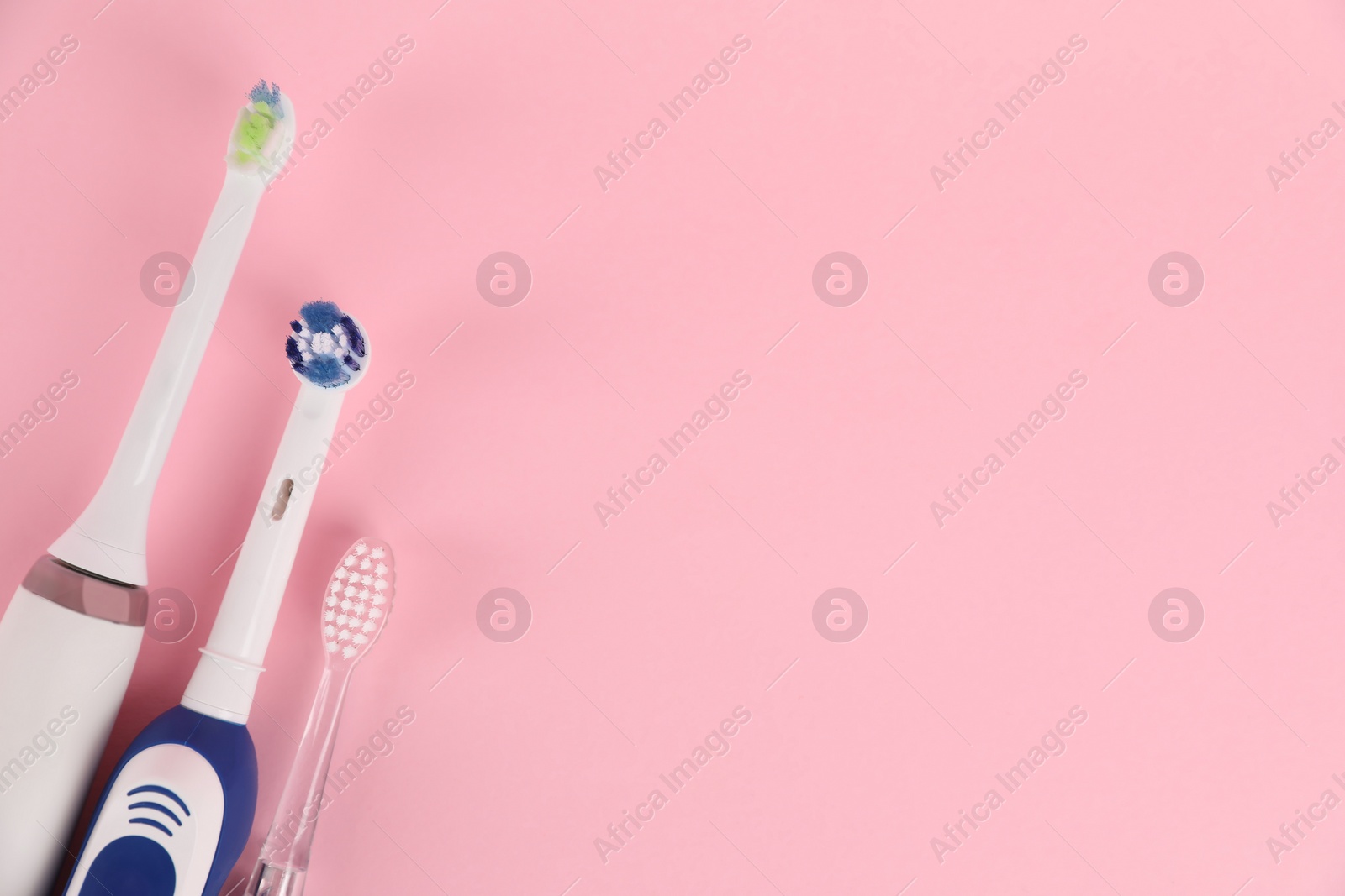 Photo of Electric toothbrushes on pink background, flat lay. Space for text