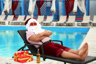 Authentic Santa Claus on lounge chair near pool at resort