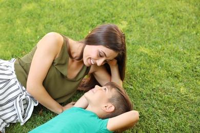 Photo of Mother with her cute child on green grass in park. Happy family