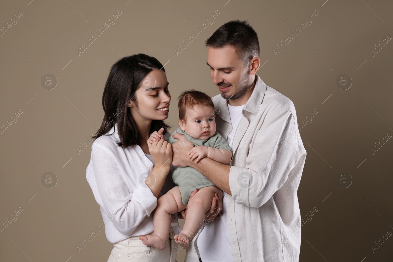 Photo of Happy family. Couple with their cute baby on beige background