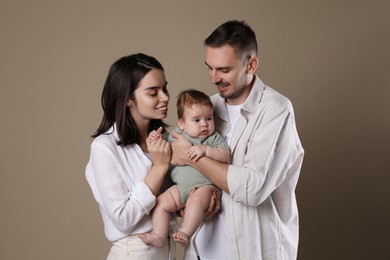 Happy family. Couple with their cute baby on beige background