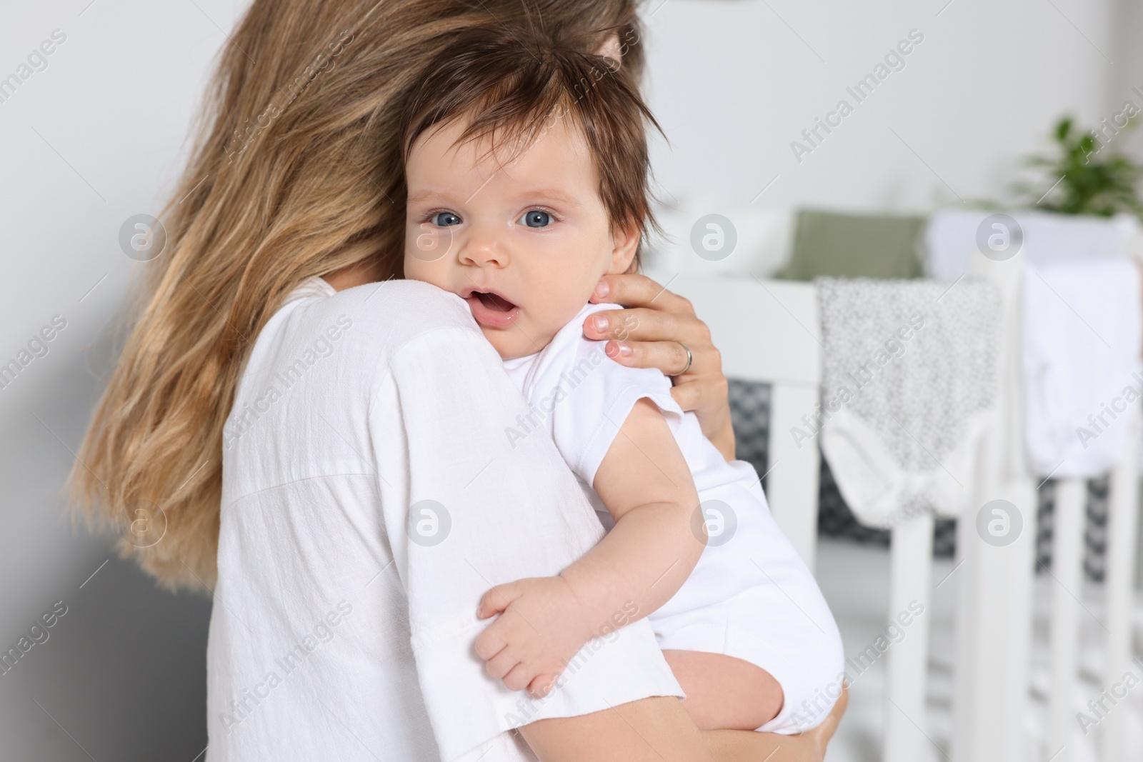 Photo of Mother hugging her cute little baby indoors