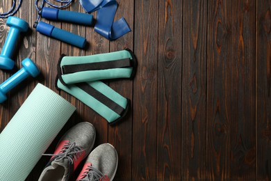 Photo of Turquoise weighting agents and sport equipment on wooden table, flat lay. Space for text