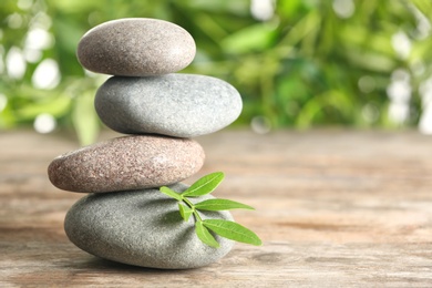 Spa stones and bamboo leaves on table against blurred background. Space for text