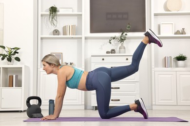 Online fitness trainer. Woman doing exercise near smartphone at home