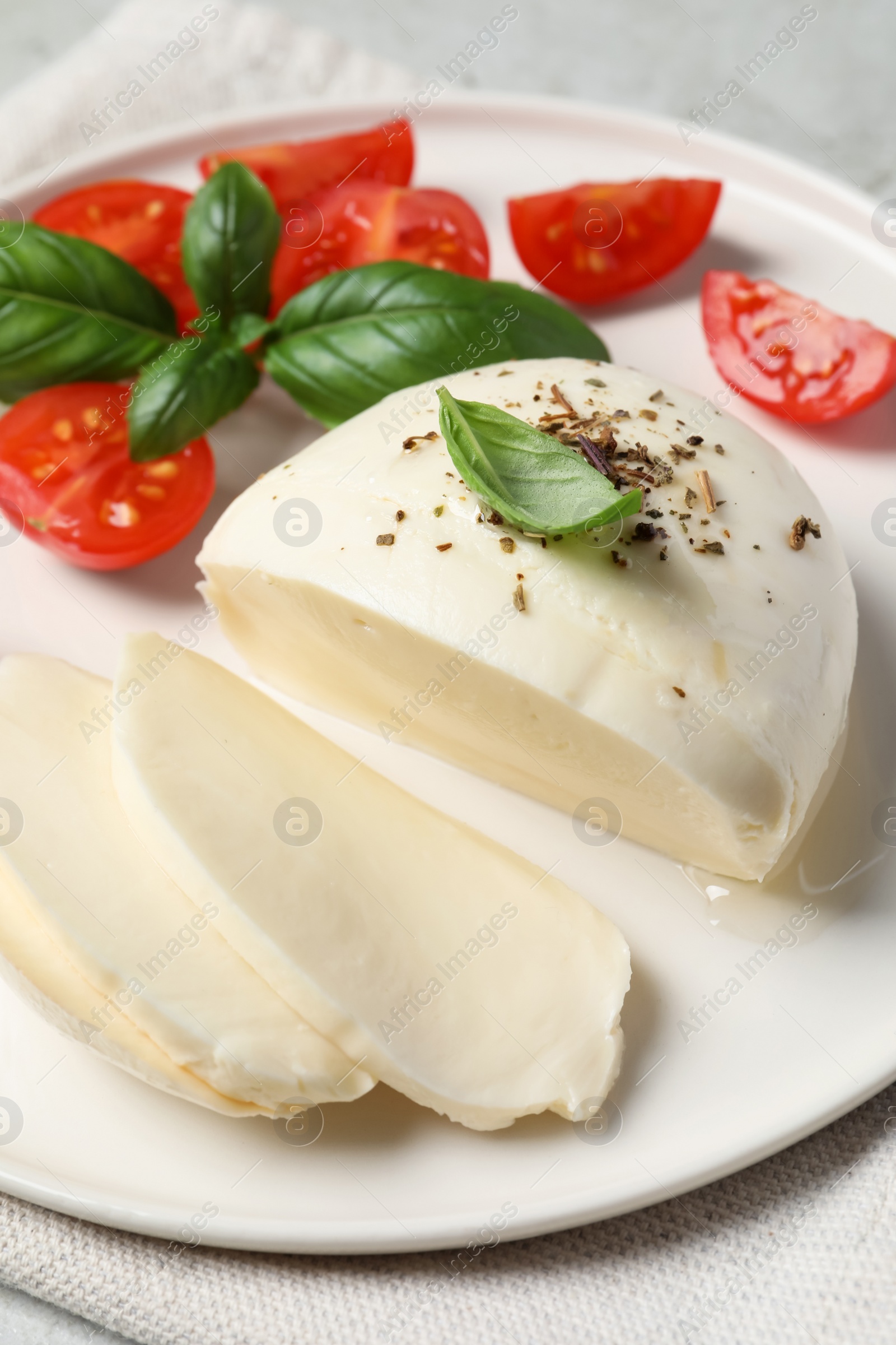 Photo of Delicious mozzarella with tomatoes and basil leaves on table, closeup